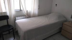 Un dormitorio con una cama blanca y una ventana. en Beachfront Apartment with Sea Views & Private Parking, en Sant Pol de Mar