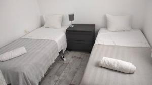 2 bedden in een kleine kamer met witte lakens bij Beachfront apartment with private parking in San Pol de Mar
