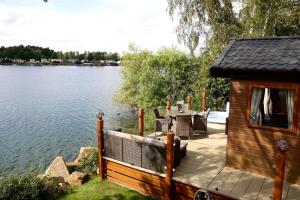 a cabin on a lake with a table and chairs at Fable Lodge Tattershall Lakes - luxury lakeside lodge with hot tub in Tattershall