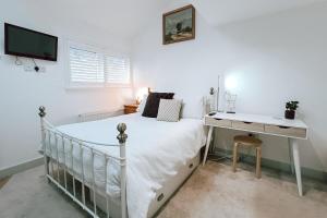 a white bedroom with a bed and a desk at The Pembroke Studio By Richmond Park in Kingston upon Thames