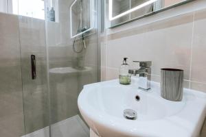 a white bathroom with a sink and a shower at The Pembroke Studio By Richmond Park in Kingston upon Thames