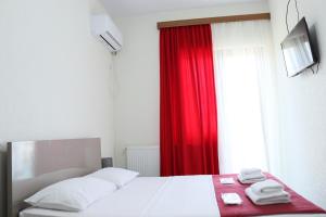 - une chambre avec un lit et un rideau rouge dans l'établissement Hotel West Face, à Koutaïssi