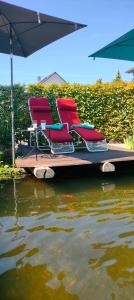 two chairs and an umbrella on a boat in the water at Moderne Vintage Ferienwohnung in Bad Schussenried