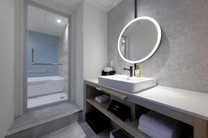 a white bathroom with a sink and a mirror at Hotel Kintetsu Universal City in Osaka