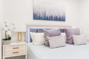 a white bedroom with a bed with purple pillows at 316 Footloose #3 in Hollywood +22 photos