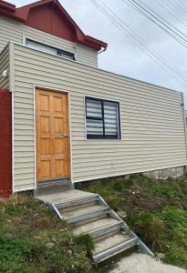 een huis met een houten deur en een trap aan de voorkant bij ROTUNDO APART in Puerto Natales