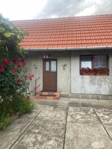 een huis met een rood dak en een deur en bloemen bij Casa Anita in Sighişoara