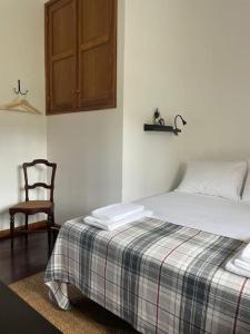 1 dormitorio con 1 cama, armario de madera y silla en Casa da Pedrada, en Ponte da Barca