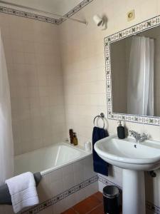 a bathroom with a sink and a tub and a mirror at Casa da Pedrada in Ponte da Barca
