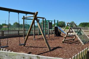a playground with two swings and a slide at Clearwater 28, Wild Briar - P in Somerford Keynes