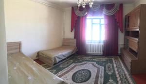 Habitación con 2 camas, ventana y alfombra. en Welcome Guest House, en Tokmok