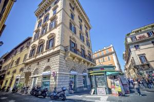 wysoki budynek z motocyklami zaparkowanymi przed nim w obiekcie Little Queen Relais w Rzymie