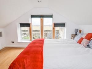 a bedroom with a large white bed with a red blanket at Ash Tree Barn in Clayton