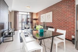 a dining room with a brick wall and a table and chairs at Urban Oasis Apartments at The Vantage in Johannesburg