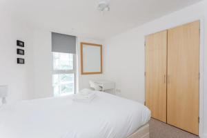 a white bedroom with a large bed and a wooden cabinet at Bright & Airy 1 Bedroom Apartment in Trendy Peckham in London