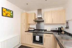 a kitchen with wooden cabinets and a stove top oven at Bright & Airy 1 Bedroom Apartment in Trendy Peckham in London