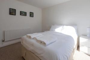 a white bedroom with a bed with white sheets and pillows at Bright & Airy 1 Bedroom Apartment in Trendy Peckham in London