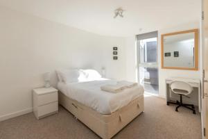 a white bedroom with a bed and a desk at Bright & Airy 1 Bedroom Apartment in Trendy Peckham in London