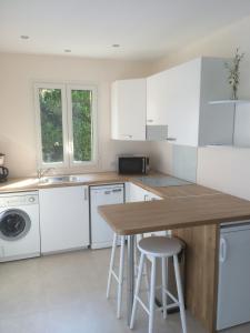 uma cozinha com armários brancos e um balcão de madeira em Les Jasmins em Sainte-Maxime