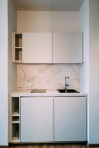 a kitchen with white cabinets and a sink at Hotel Amalia - Boutique Hotel in Landshut