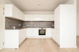a kitchen with white cabinets and a wooden floor at Modern Buckingham Palace Apartment in London