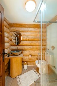 a bathroom with wooden walls and a sink and a mirror at Fox Wood House in Ciobotani