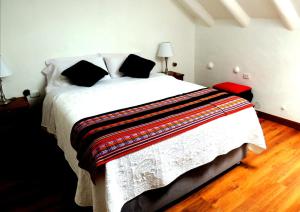 um quarto com uma grande cama branca com almofadas pretas em Kori Gems Inn em Cusco