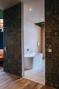 a bathroom with a tub and a wall with a patterned wall at Hotel Amalia - Boutique Hotel in Landshut