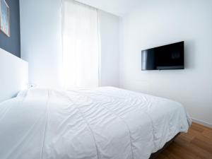 a white bedroom with a bed and a tv on a wall at Appartements proche Croisette, Casino, plages, centre ville et Gare in Cannes