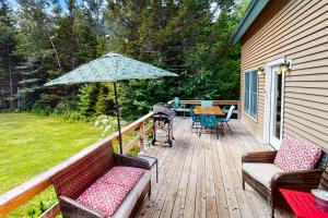 una terrazza in legno con sedie e ombrellone di Cabin in the Woods a Owls Head
