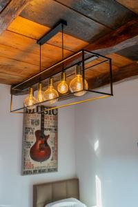 un lampadario pendente appeso a un soffitto con una chitarra appesa al muro di Arena Rooms Zagreb a Zagabria