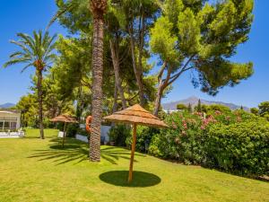 een park met palmbomen en parasols in het gras bij Cubo's Torre Andalucia Marbella Apartment in Marbella