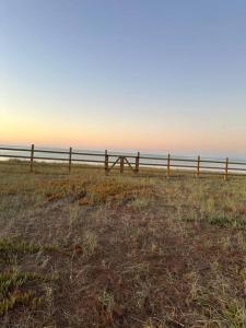 a wooden fence in a field near the ocean at Tiny house - Playa in Arauco