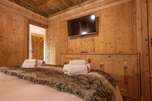 1 dormitorio con 1 cama y TV en la pared en Casa Aquila, en Cortina dʼAmpezzo