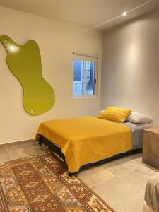 1 dormitorio con 1 cama con una manta amarilla grande en Natural creative space in downtown Cabo!, en Cabo San Lucas