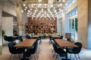 ein Restaurant mit Holztischen, Stühlen und Kronleuchtern in der Unterkunft Atwell Suites - Miami Brickell, an IHG Hotel in Miami