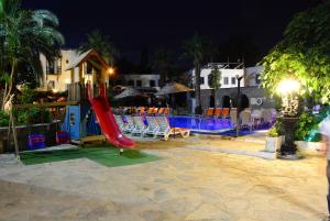 ein Spielplatz mit Rutsche und Stühlen bei Nacht in der Unterkunft Bodrum Park Hotel in Gümbet