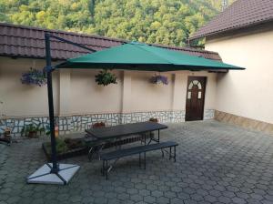 a picnic table with a green umbrella in front of a building at Casa Zorilor in Şugag