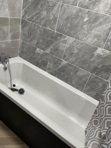 a white bath tub in a bathroom with a tile wall at Bethel Apartments in Leeds