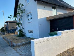 a white house with a fence in front of it at 200 m til havet - fri adgang til svømmehal in Thyborøn