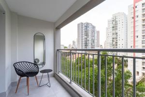 balcón con silla y vistas a los edificios en Charlie Hotel Atmosfera Paulista en São Paulo