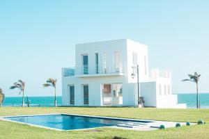 a house with a swimming pool in front of the ocean at Karibao Resort Town in Playas