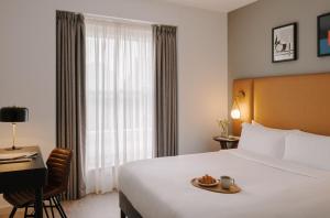 ein Hotelzimmer mit einem Bett mit einem Teller Essen drauf in der Unterkunft Sonder The Henry in London