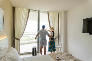 Karibao Resort Town في بلاياس: رجل وامرأة ينظران من نافذة غرفة فندق