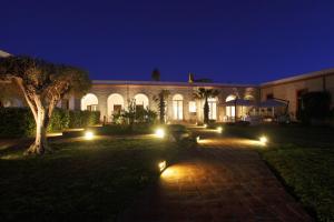 a building with lights in the yard at night at I Pretti Resort in Favignana