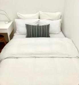 een wit bed met witte kussens en een tafel bij Appartement confortable et complet in Clichy