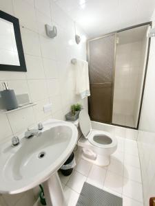 a white bathroom with a toilet and a sink at Royal Rooms in Bogotá