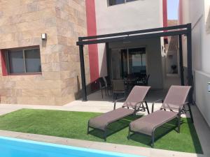 un patio con 2 sillas y una piscina en Villa Inda en Gran Tarajal