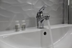 a bathroom sink with a faucet and two bottles on it at Abate Gimma Apartment in Bari