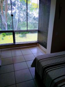 a bedroom with a bed and a window with a view at Apartamento no Residencial Swiss Jd Europa in Santa Cruz do Sul